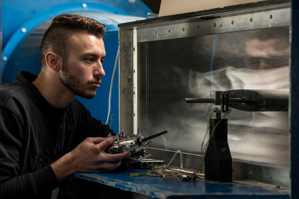 Undergraduate student Noah Richardson observes changes made from a controller inside the subsonic wind tunnel for lab work